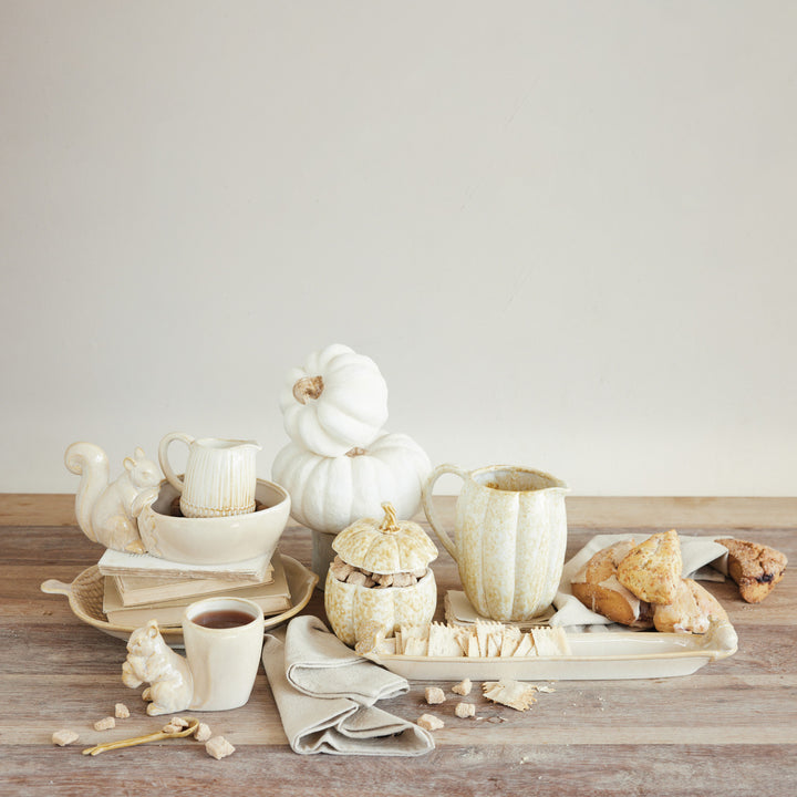 Autumnal table setting with pumpkins, mugs, and cookies on a wooden surface.