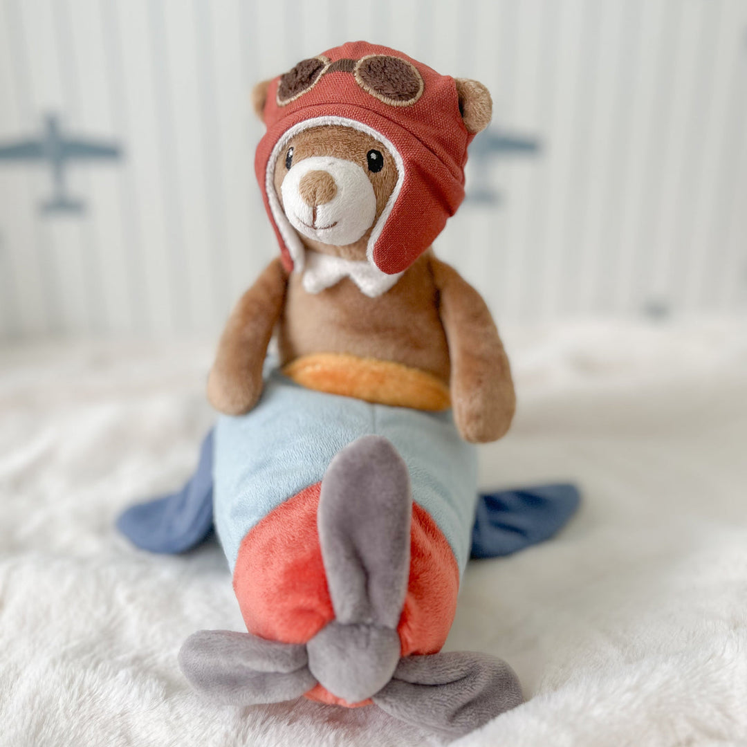 Stuffed toy rabbit in an aviator outfit sitting on a soft surface with a blurred background