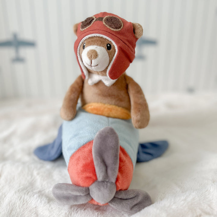Stuffed toy rabbit in an aviator outfit sitting on a soft surface with a blurred background