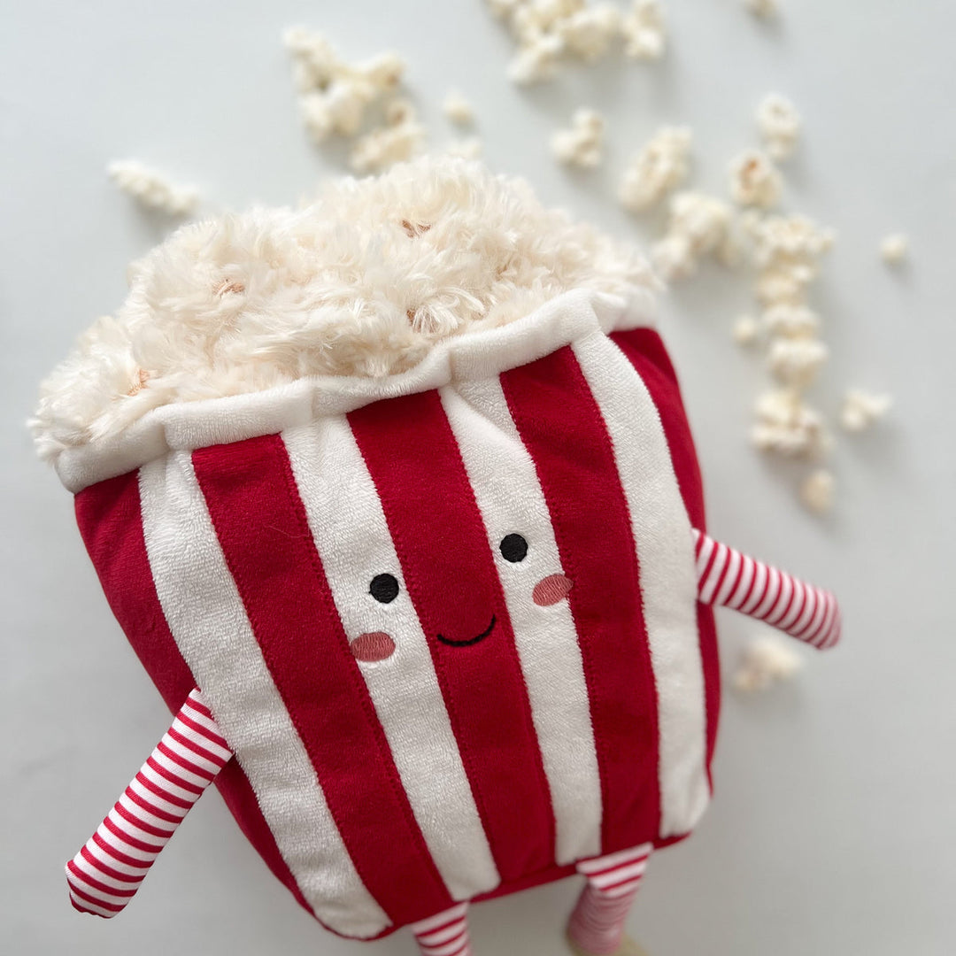 Red and white striped plush toy with a happy face on a light gray background