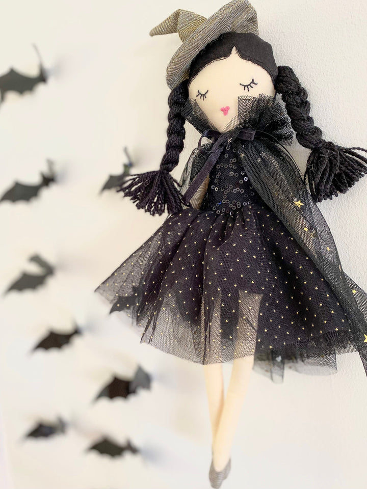 Halloween-themed doll with black dress and witch hat on a white background with black bats.