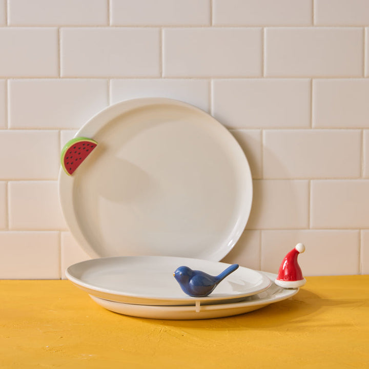 Set of ceramic plates with decorative elements on a yellow surface and tiled wall background