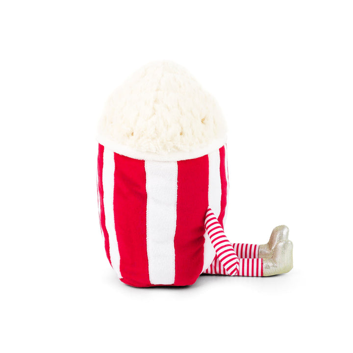 A plush toy shaped like a popcorn bucket, featuring red and white vertical stripes, a cream-colored popcorn-topped head, and striped legs with metallic silver feet, shown on a plain white background.