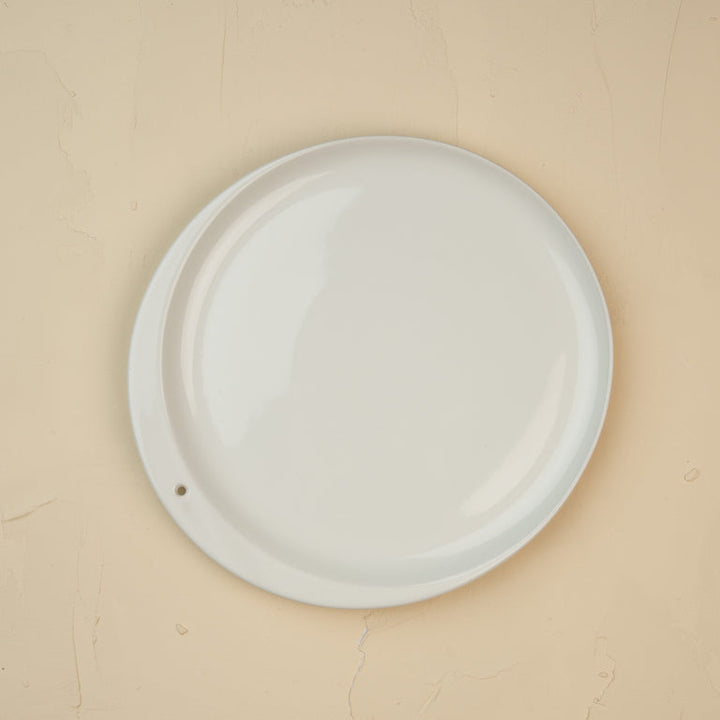 Round white ceramic plate on a beige background