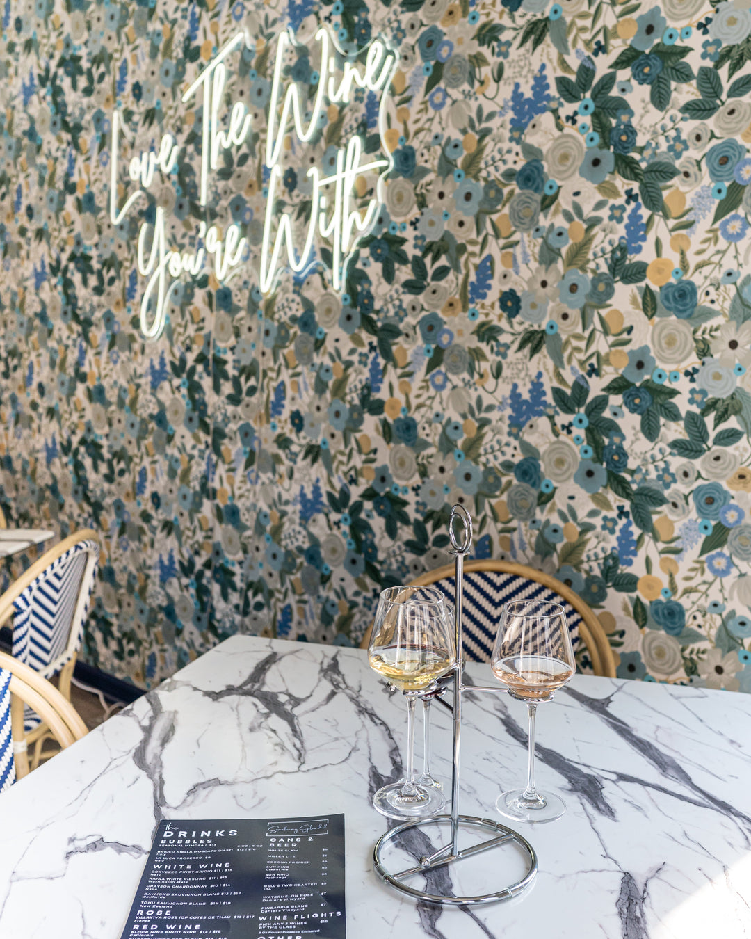 Restaurant interior with floral wallpaper, marble table, and wine glasses at something Splendid