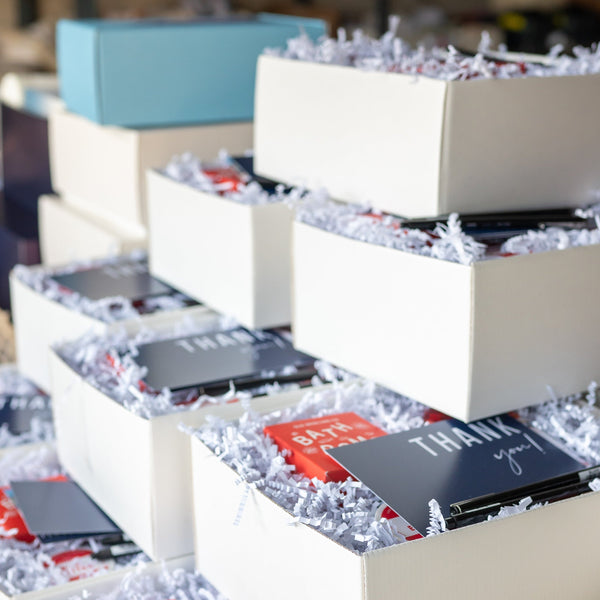 Stack of white boxes with products inside, set against a blurred indoor background.